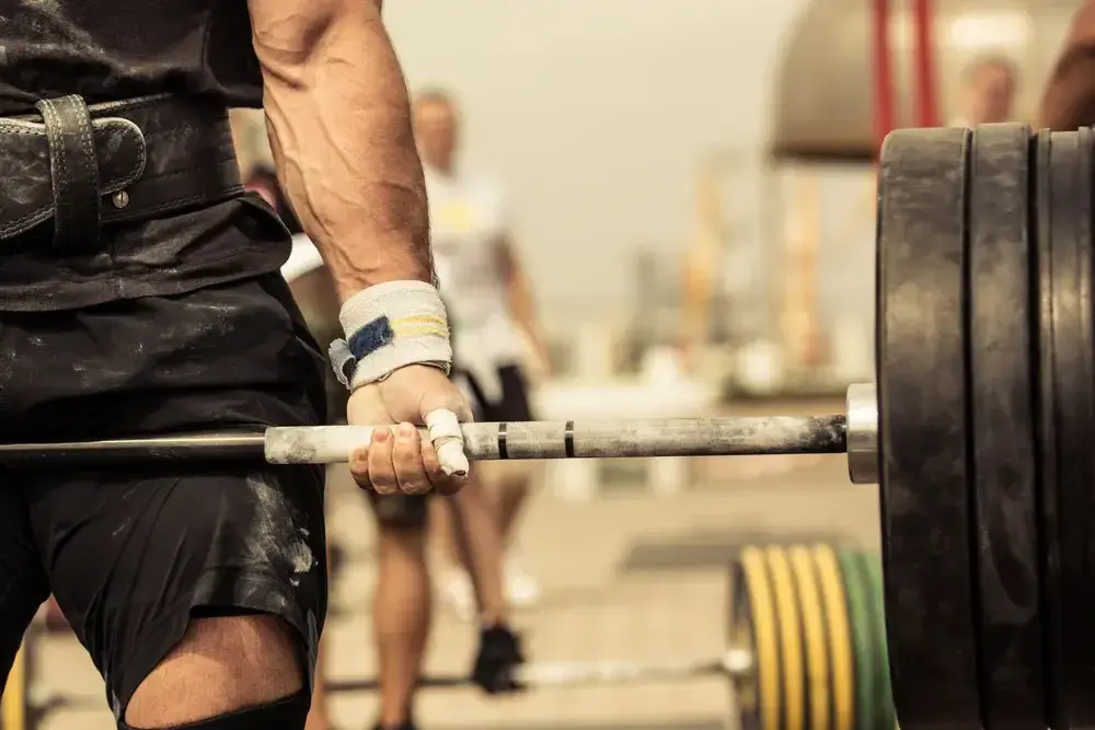 Closeup portrait of professional bodybuilder workout with barbell outdoors